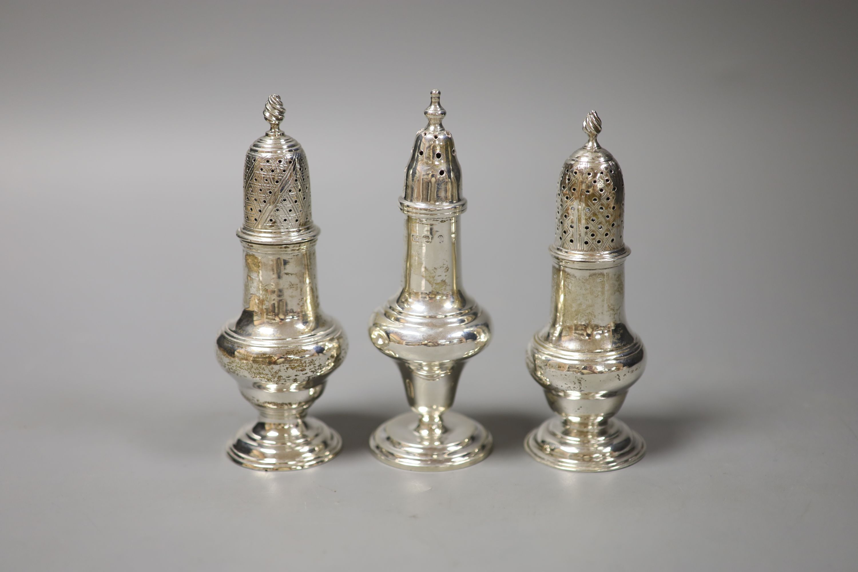 A George III baluster silver pepper, London 1771, another similar pepper, London 1769 and a later pepper with urn finial (3), tallest 14.6cm,